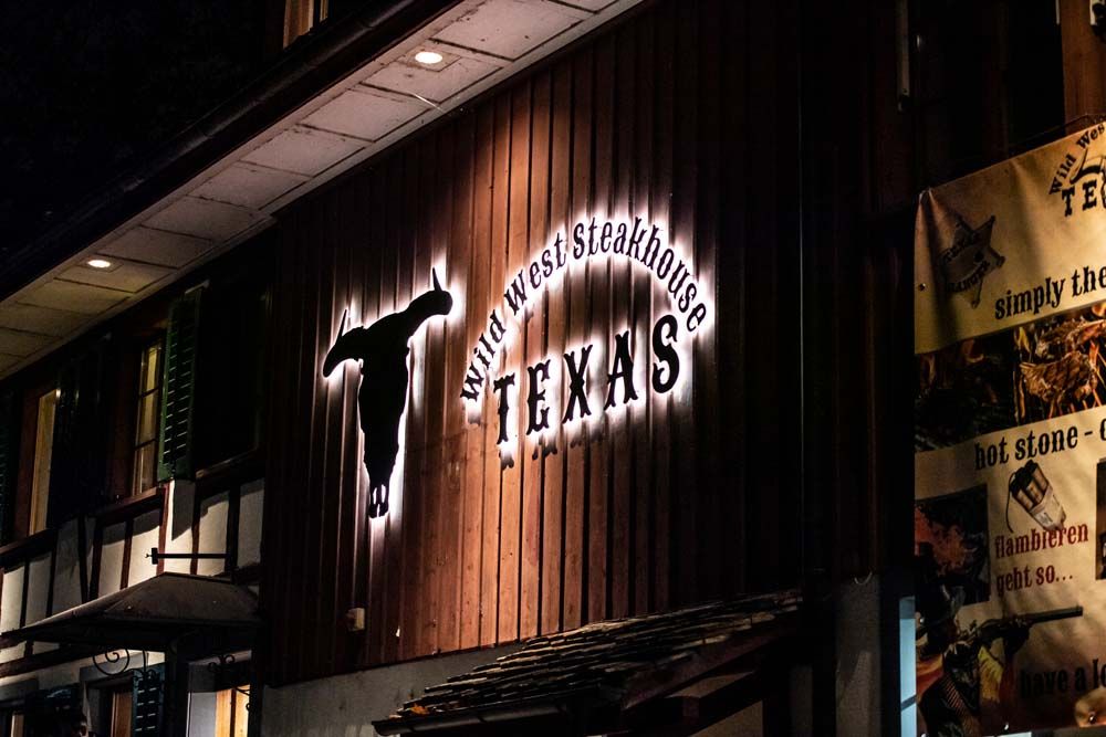 Beleuchtete Fassade des Wild West Steakhouse Texas bei Nacht